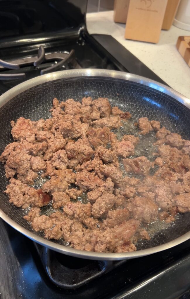 Ground beef browning in a skillet for slow cooker taco soup