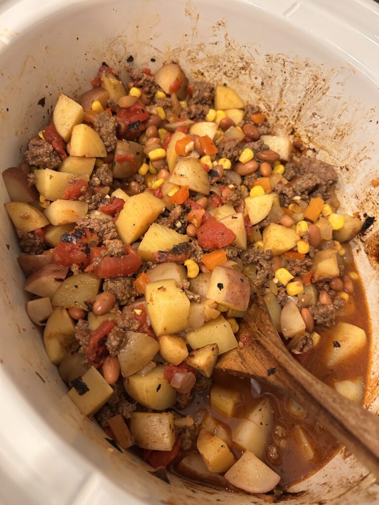 Slow cooker cowboy casserole fully cooked with tender potatoes before adding cheddar cheese