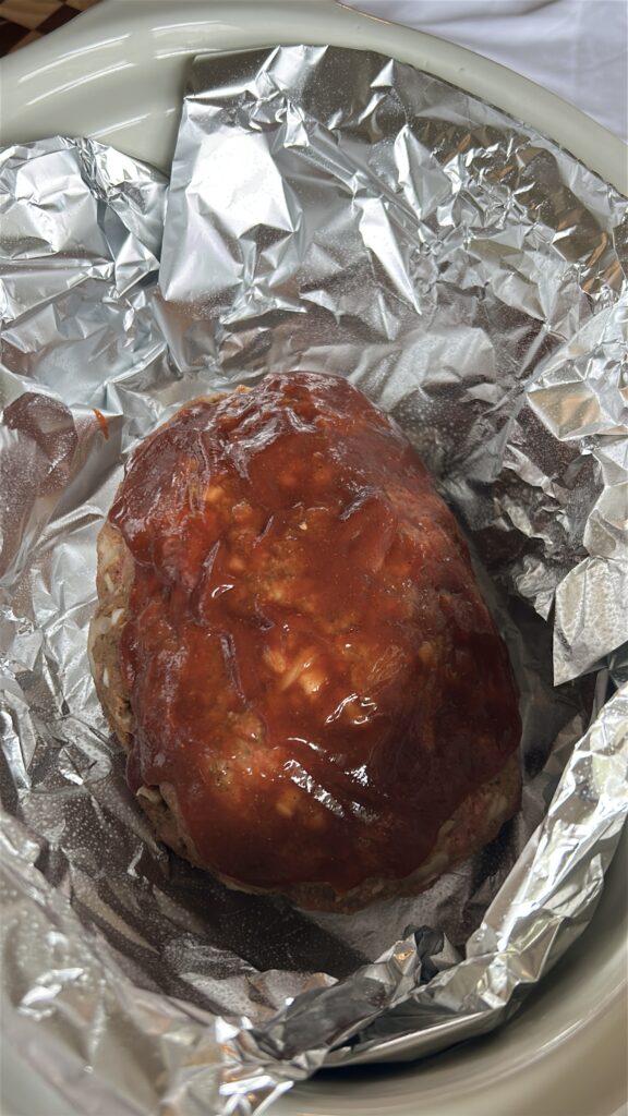 Crockpot meatloaf brushed with the first layer of sweet and tangy glaze before cooking
