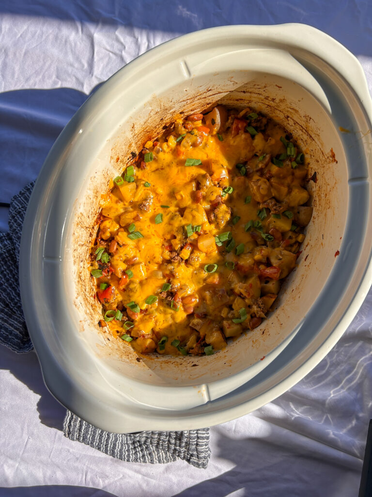 Slow cooker cowboy casserole topped with green onions and ready to serve