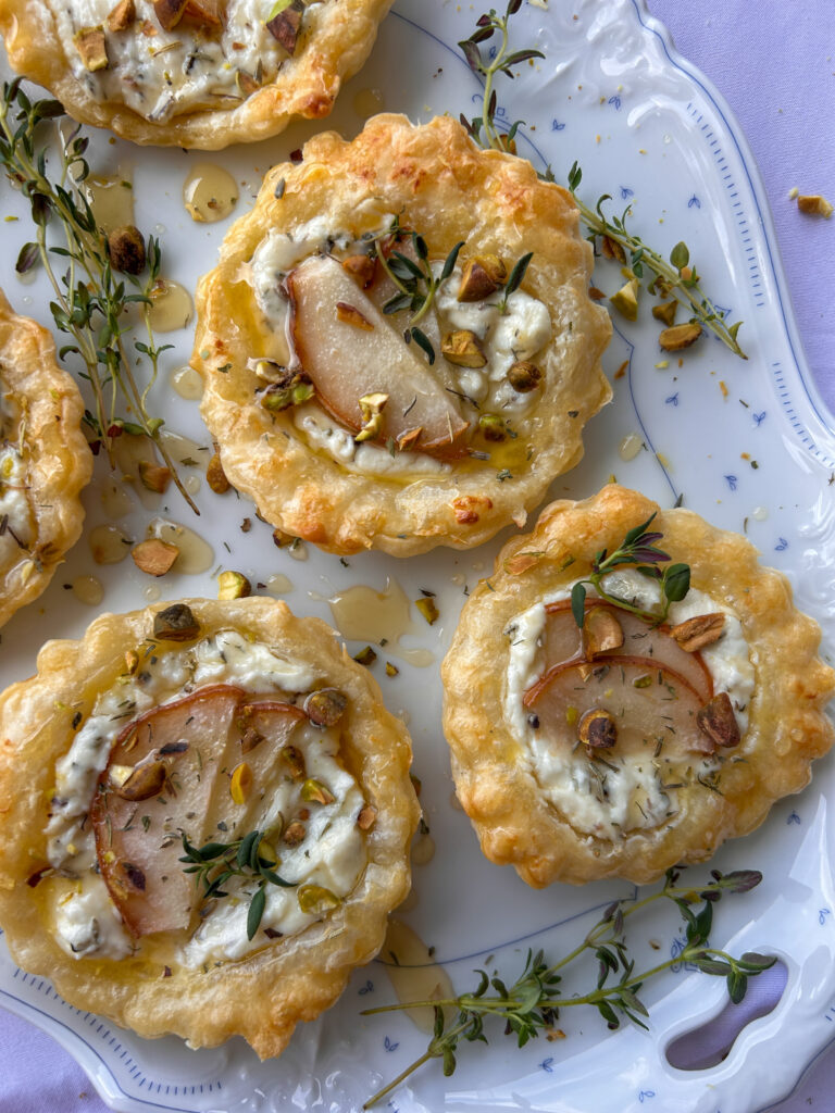 Flaky puff pastry lavender goat cheese tartlets topped with pear slices, honey, and pistachios
