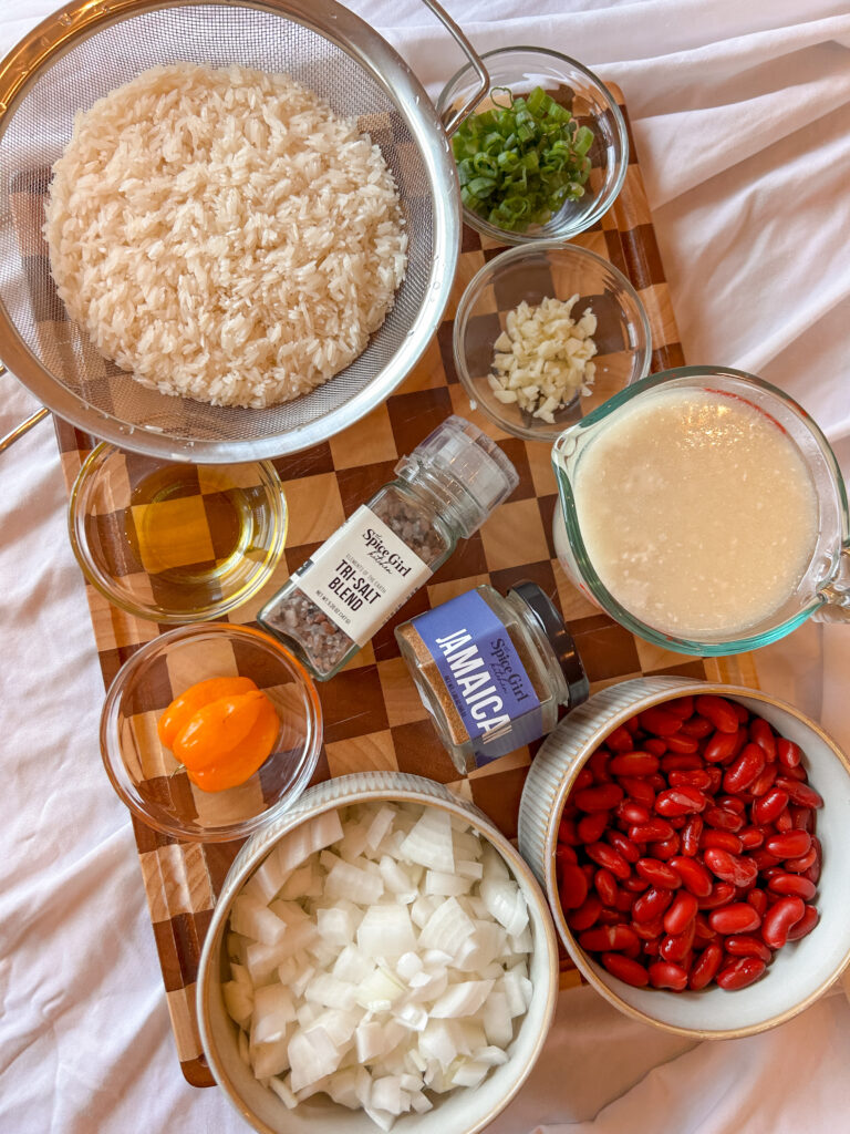 Ingredients needed to make Jamaican rice and peas including coconut milk, kidney beans, rice, and Jamaican seasoning
