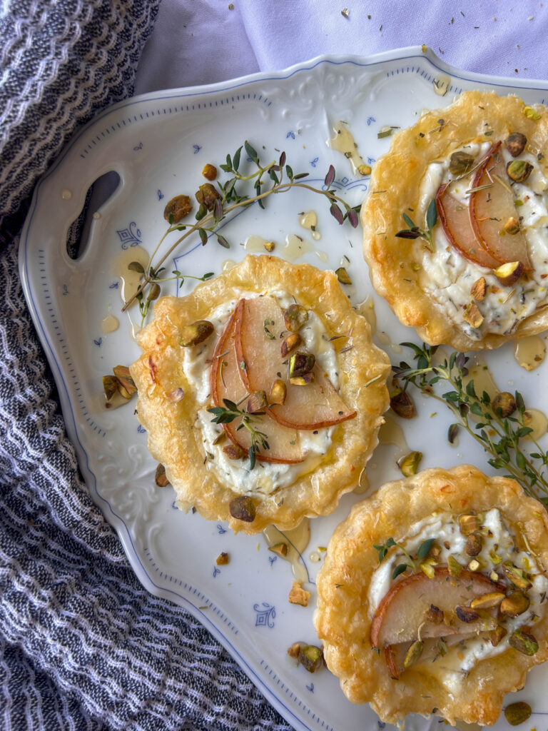 Close up of a lavender goat cheese tartlet with pear, honey, and pistachios