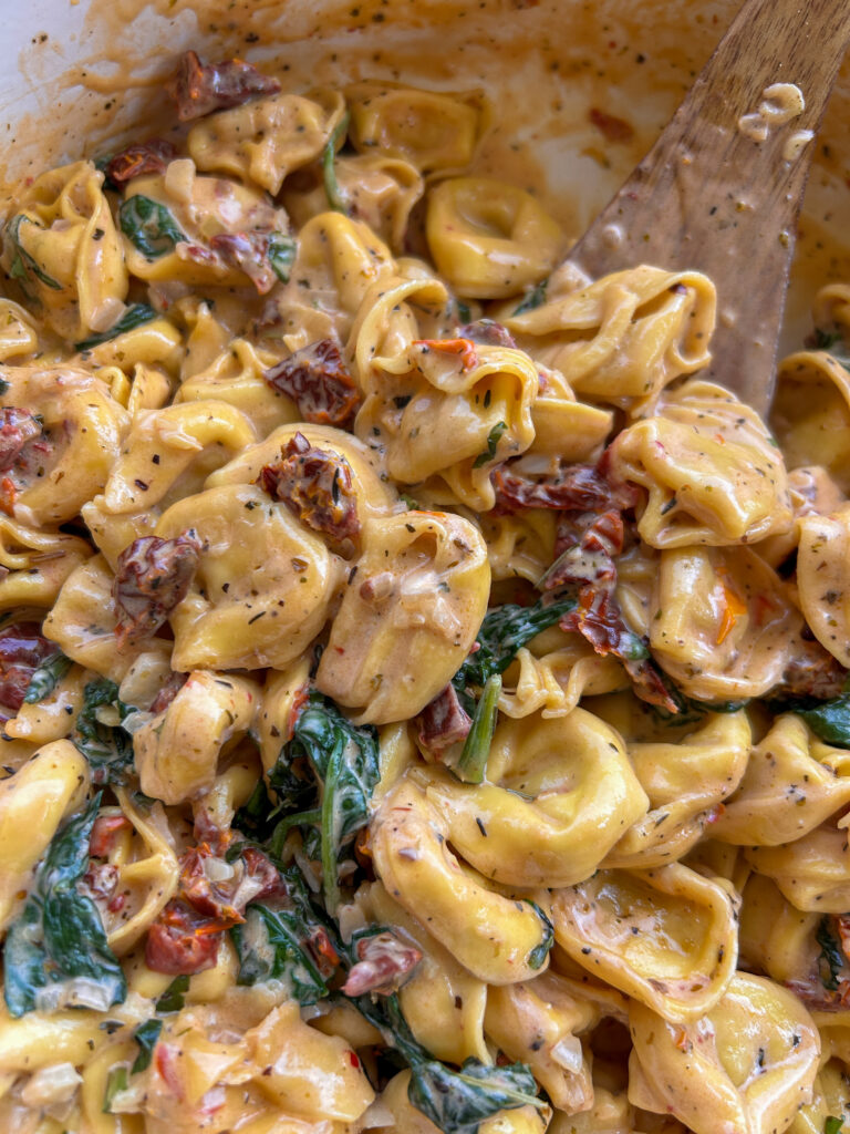 Close up of creamy Marry Me Tortellini with Parmesan cheese, sun-dried tomatoes, and fresh basil