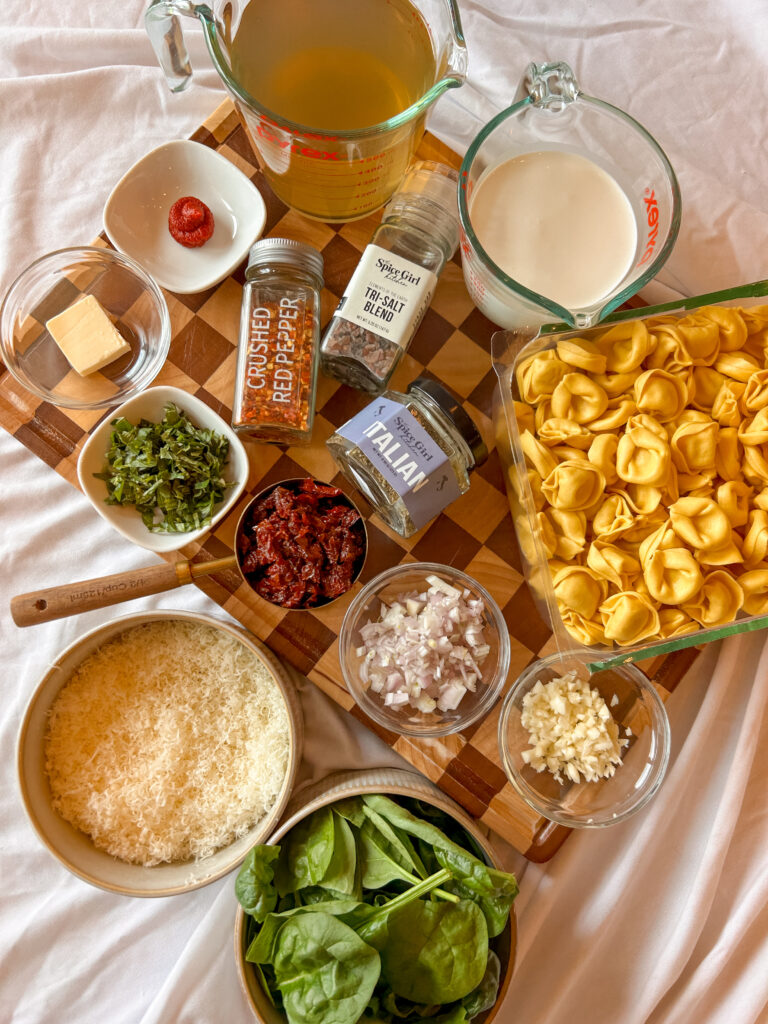 Ingredients needed to make Marry Me Tortellini including cheese tortellini, Parmesan cheese, heavy cream, spinach, sun-dried tomatoes, and Italian seasoning
