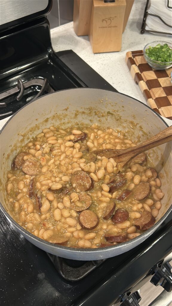 Mashing cooked white beans to create a creamy texture in white beans and sausage