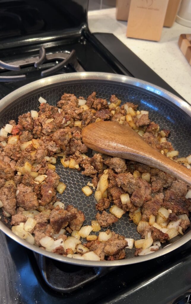 Onion, garlic, tomato paste, and Mexican seasoning cooking with ground beef