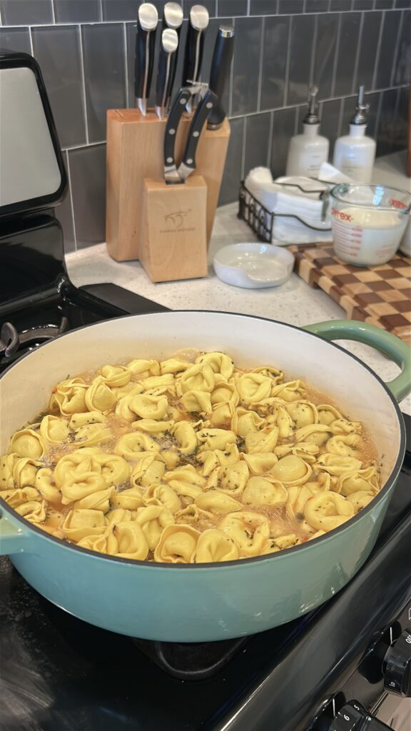 Cheese tortellini simmering in chicken broth for Marry Me Tortellini