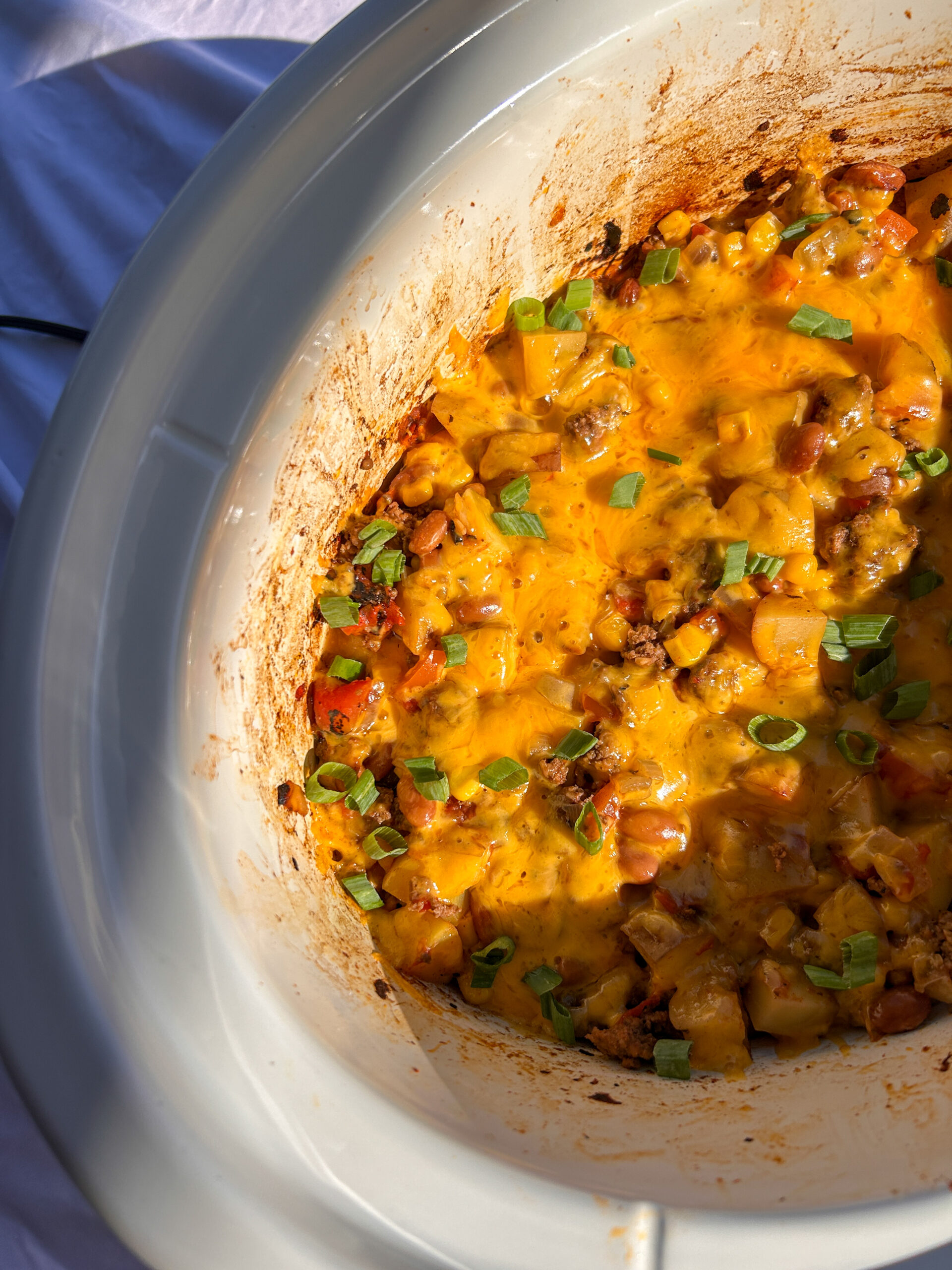 Hearty slow cooker cowboy casserole topped with melted cheddar cheese and green onions