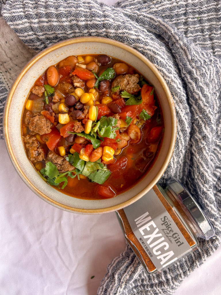 Close up of slow cooker taco soup with ground beef, beans, corn, and toppings