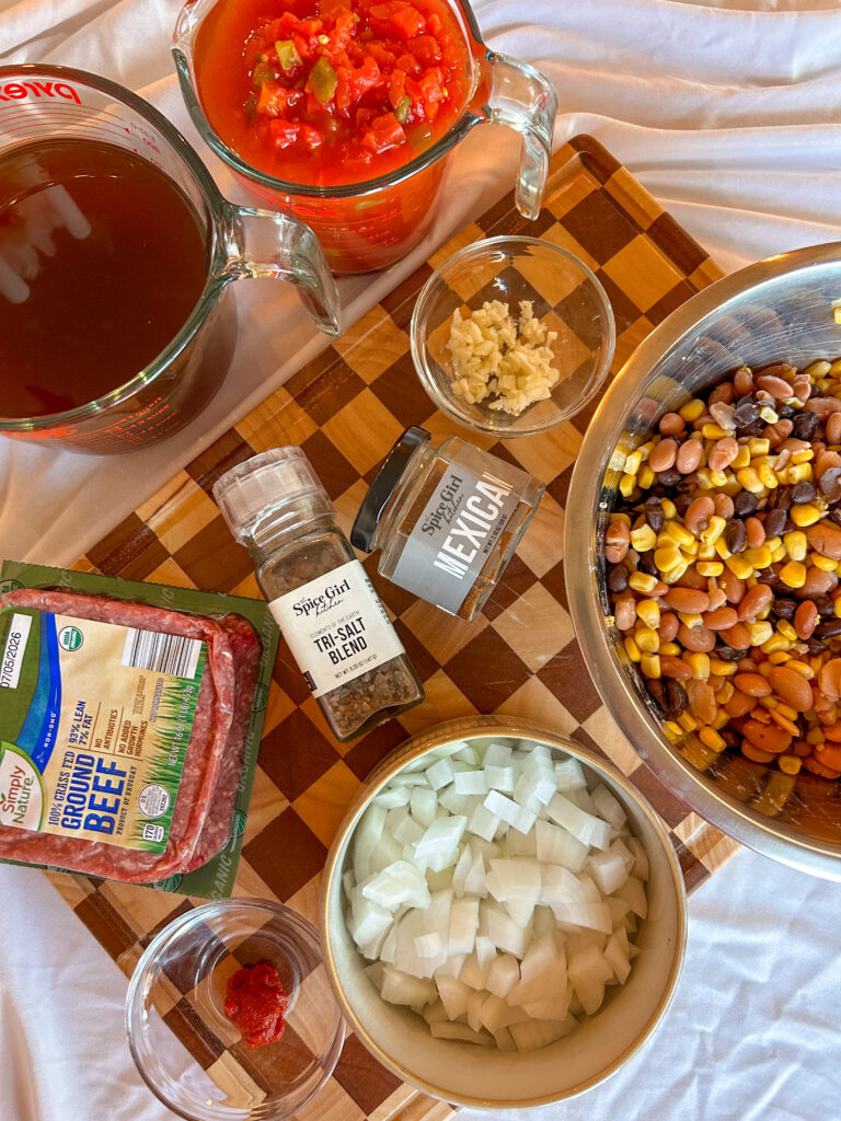Ingredients needed to make slow cooker taco soup including ground beef, beans, corn, tomatoes, and Mexican seasoning