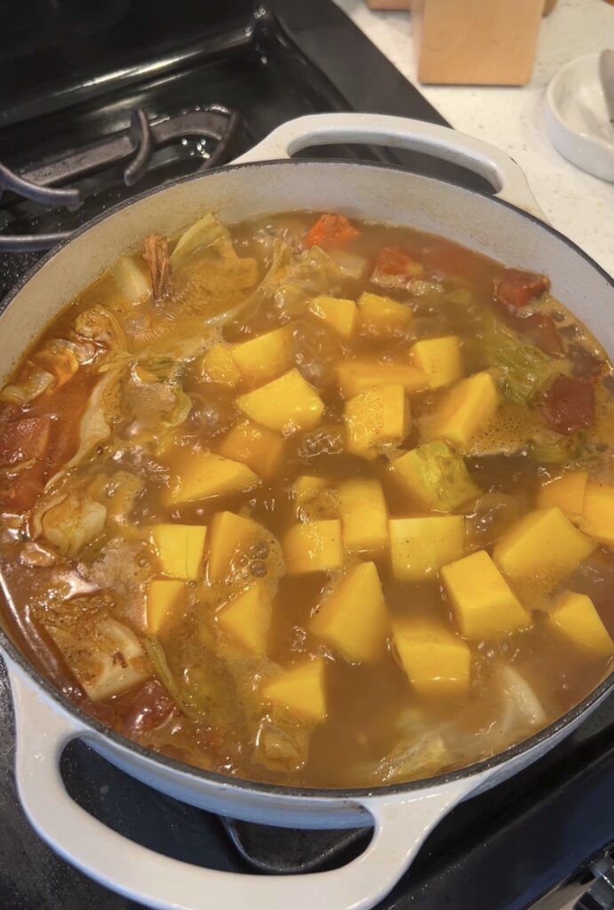 Adding butternut squash to the simmering Moroccan couscous broth