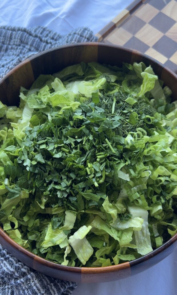 Romaine lettuce topped with fresh dill and green onions before adding dressing