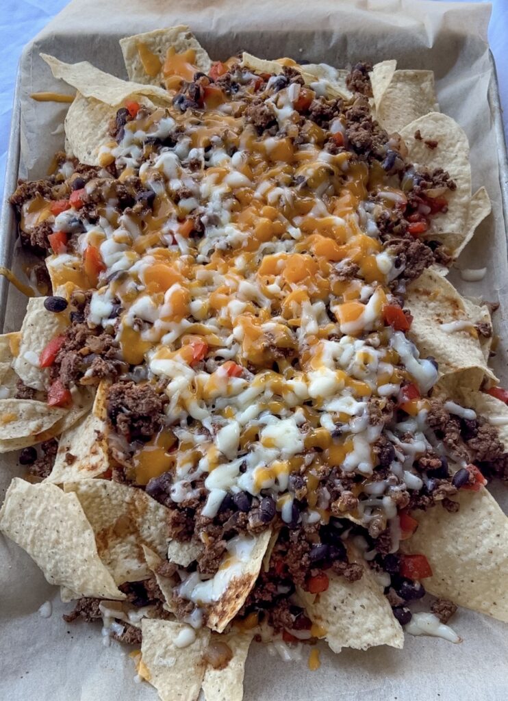 Sheet pan nachos baked until the cheddar and Monterey Jack cheese are melted and bubbly