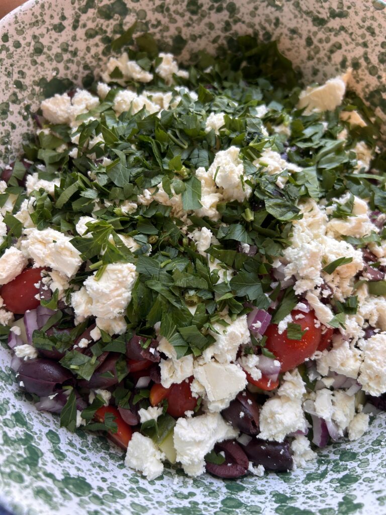 Chickpeas, vegetables, feta, and olives combined in a bowl before adding the dressing