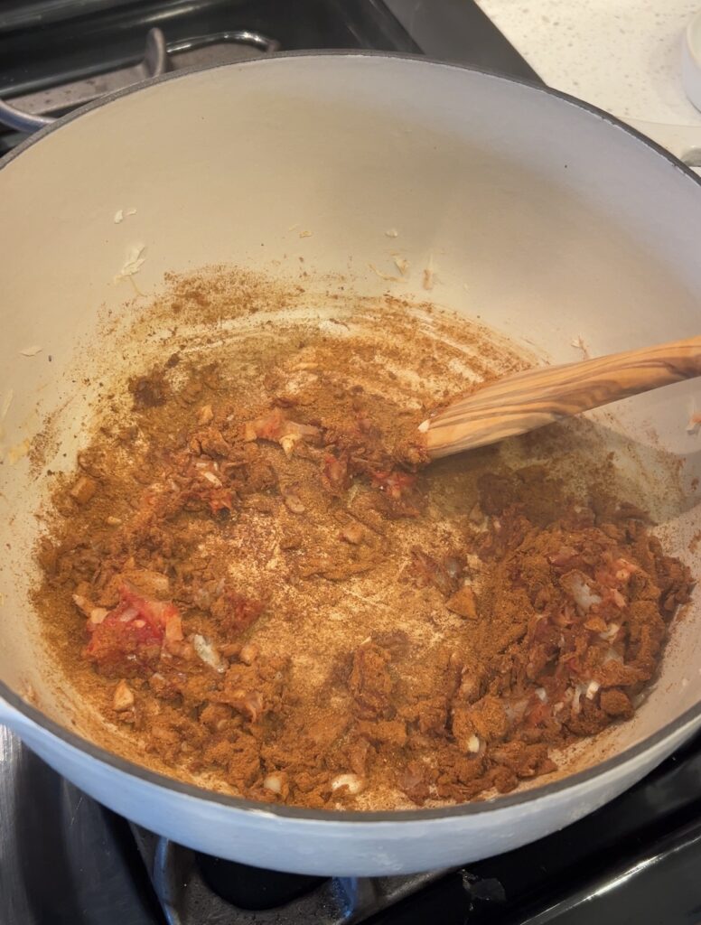 Tomato paste, garlic, and Moroccan seasoning cooking together to build the flavor base for Loubia