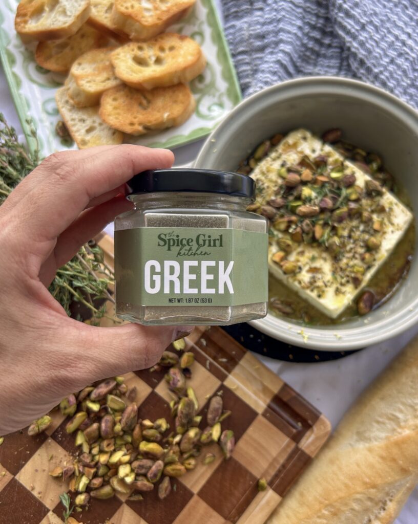 Finished baked feta topped with honey, toasted pistachios, lemon zest, and fresh thyme.
