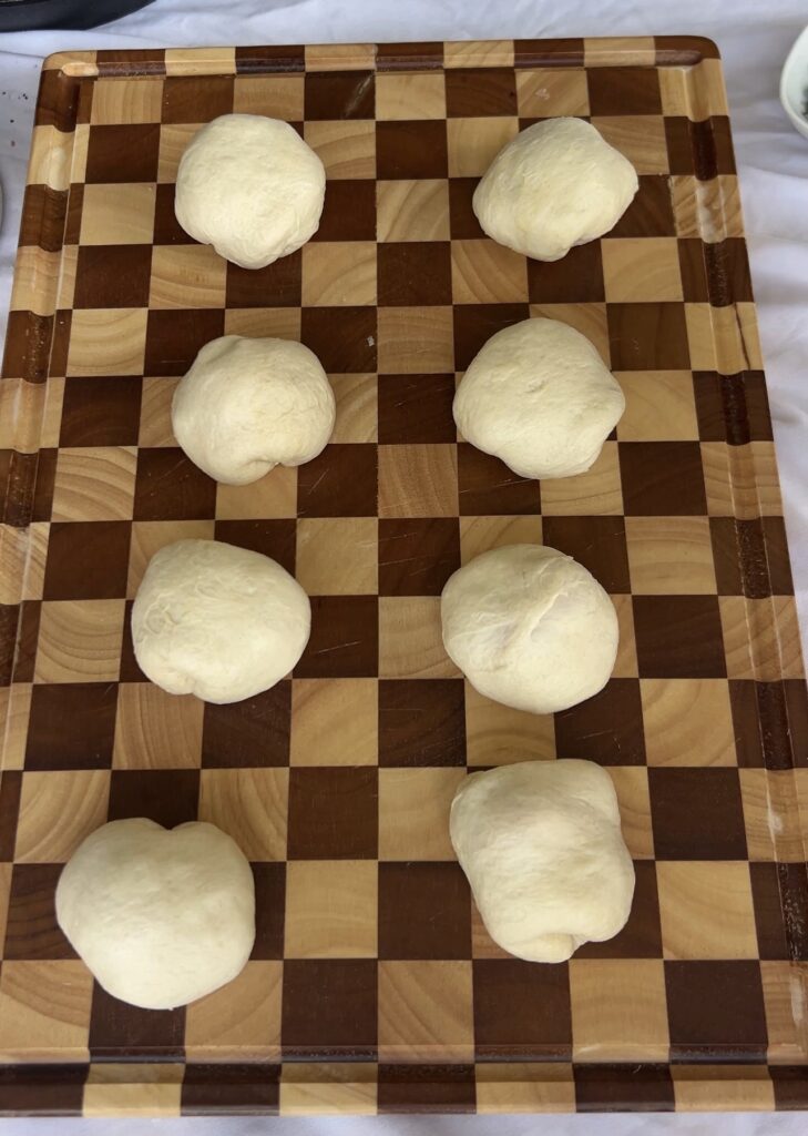 Pizza bombs sealed into smooth dough balls and arranged in a cast iron skillet before baking.