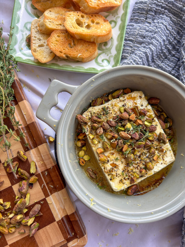 Baked feta appetizer with honey and pistachios served warm in a baking dish.