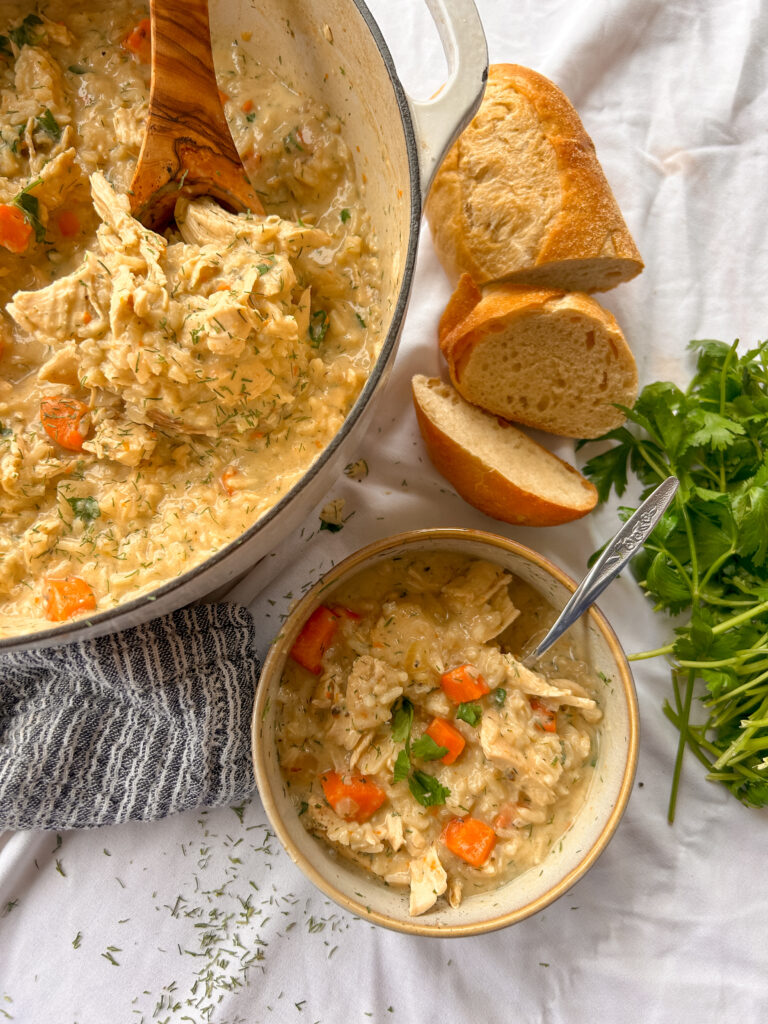 Close-up of creamy Greek lemon chicken soup with tender chicken, rice, fresh dill, and lemon