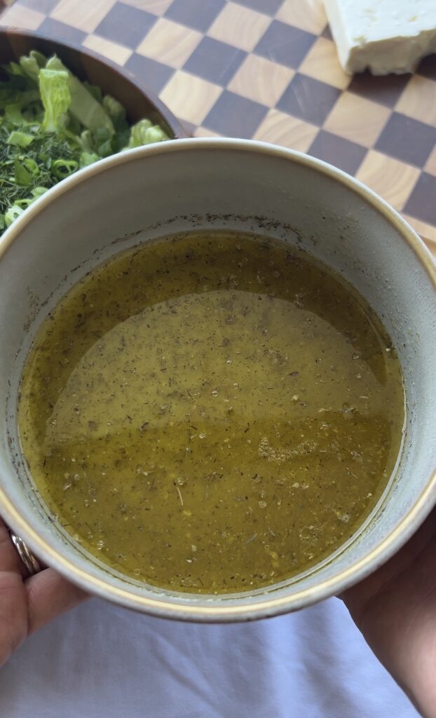 Whisking together lemon juice, olive oil, Greek seasoning, salt, and pepper for maroulosalata dressing