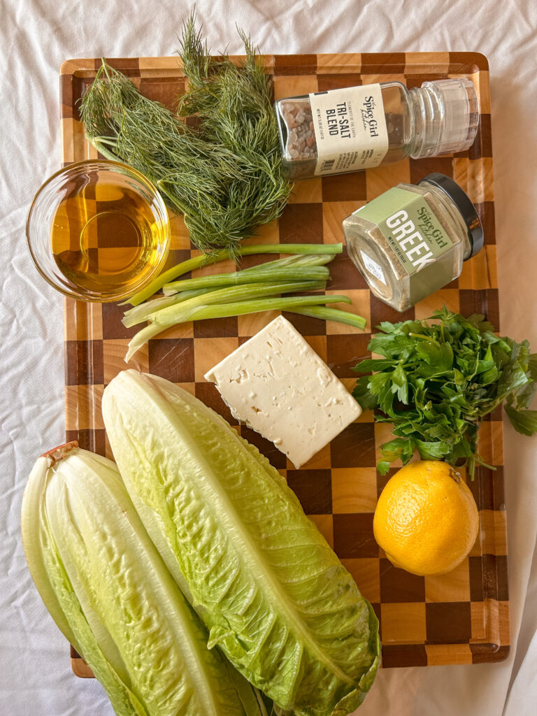 Ingredients for maroulosalata including romaine, dill, green onions, feta, lemon, olive oil, and Greek seasoning