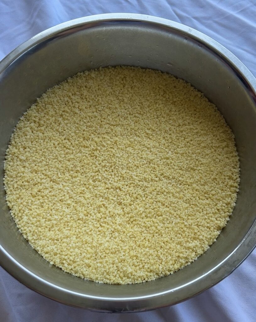 Preparing fluffy Moroccan couscous with hot broth before serving