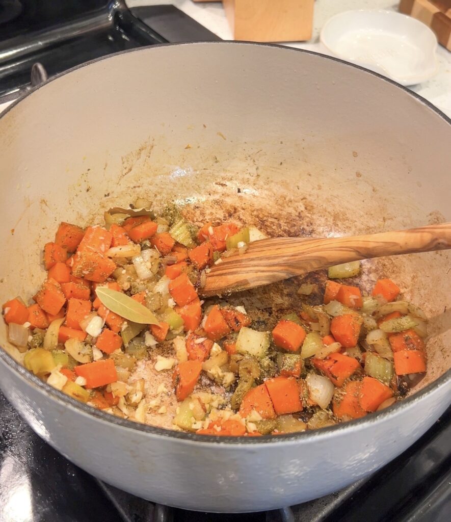 Onion, carrots, celery, and garlic sautéing for Greek lemon chicken soup