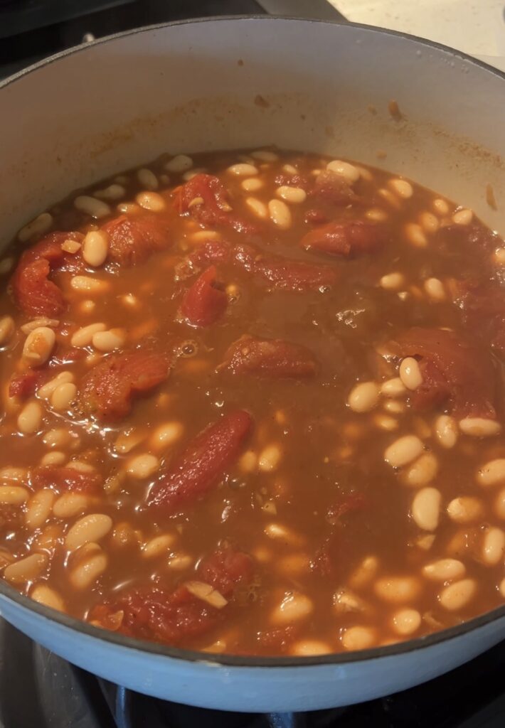 Loubia simmering in a Dutch oven with cannellini beans in a rich tomato broth
