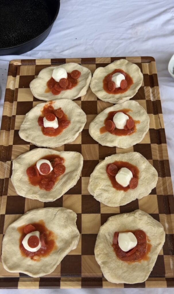 Pizza bomb filling with pizza sauce, mini pepperoni, and mozzarella cheese layered onto flattened biscuit dough.