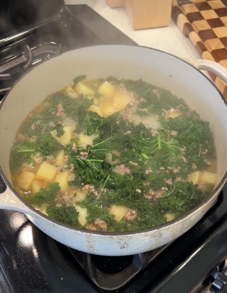 Chopped kale added to creamy sausage and potato Zuppa Toscana soup