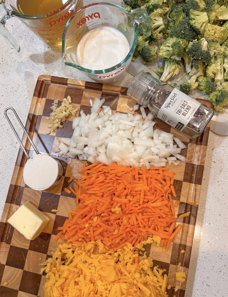 Ingredients for broccoli cheddar soup including broccoli, carrots, cheddar cheese, half-and-half, and broth