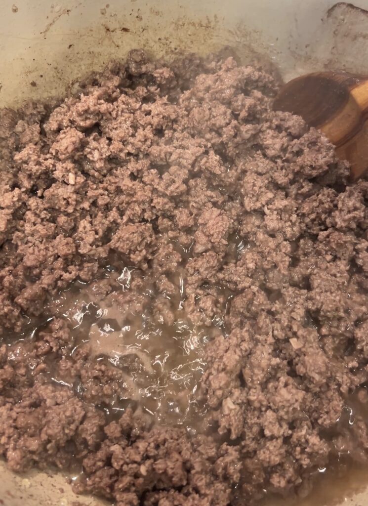 Ground bison browning in a Dutch oven for spicy bison chili