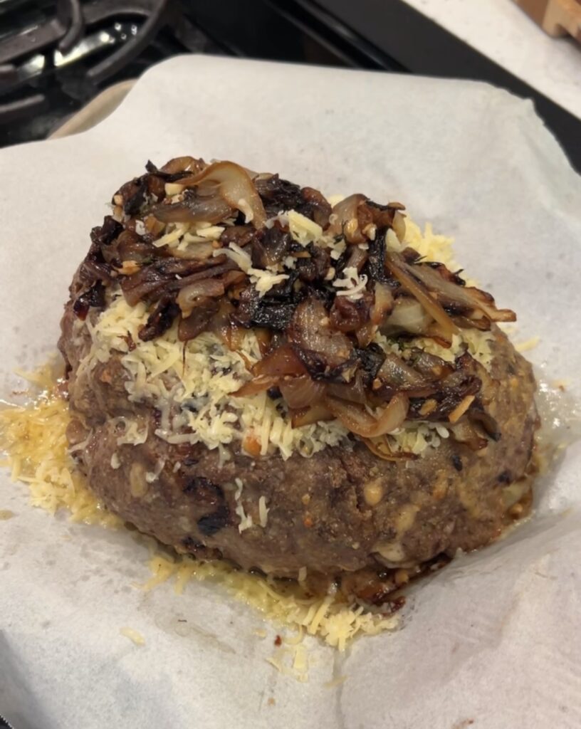 Baked meatloaf topped with caramelized onions and shredded Gruyère cheese