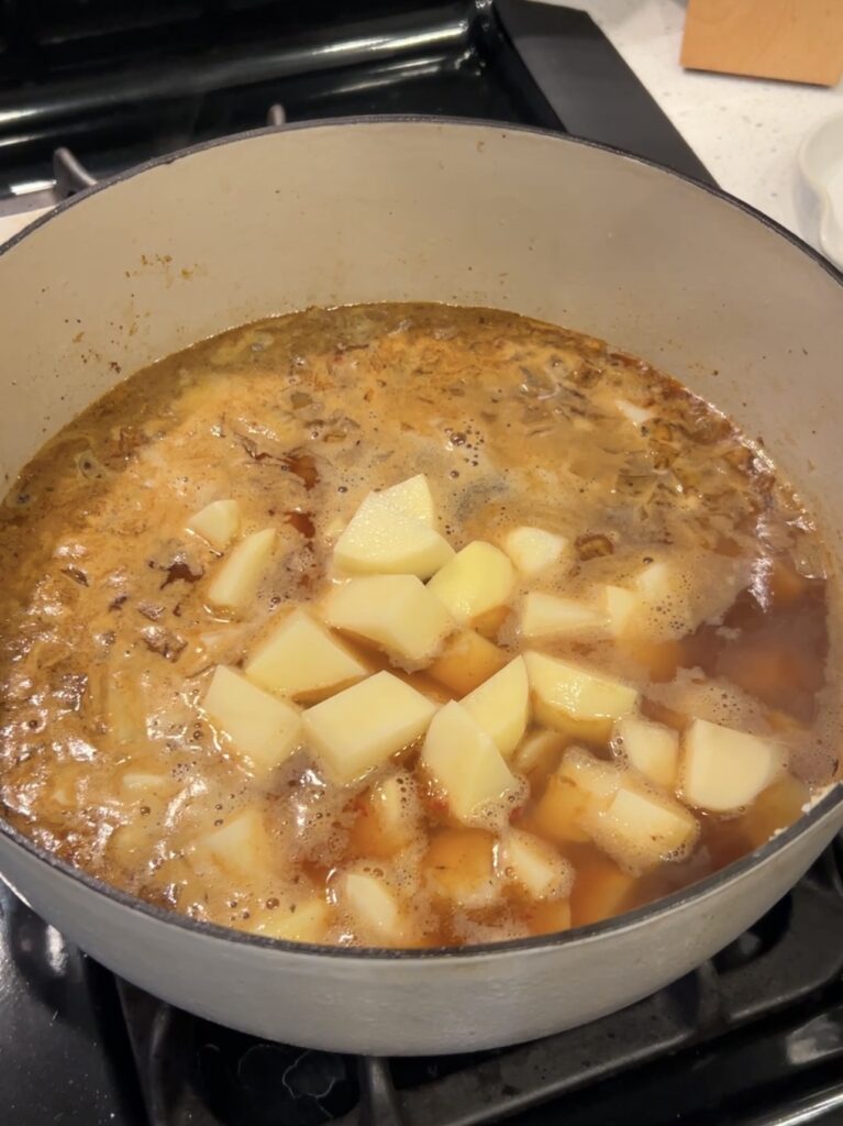 Cubed russet potatoes simmering in chicken broth for potato soup