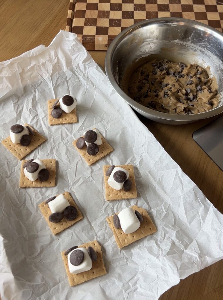 Graham cracker topped with a large marshmallow and chocolate wafers for s’mores cookies