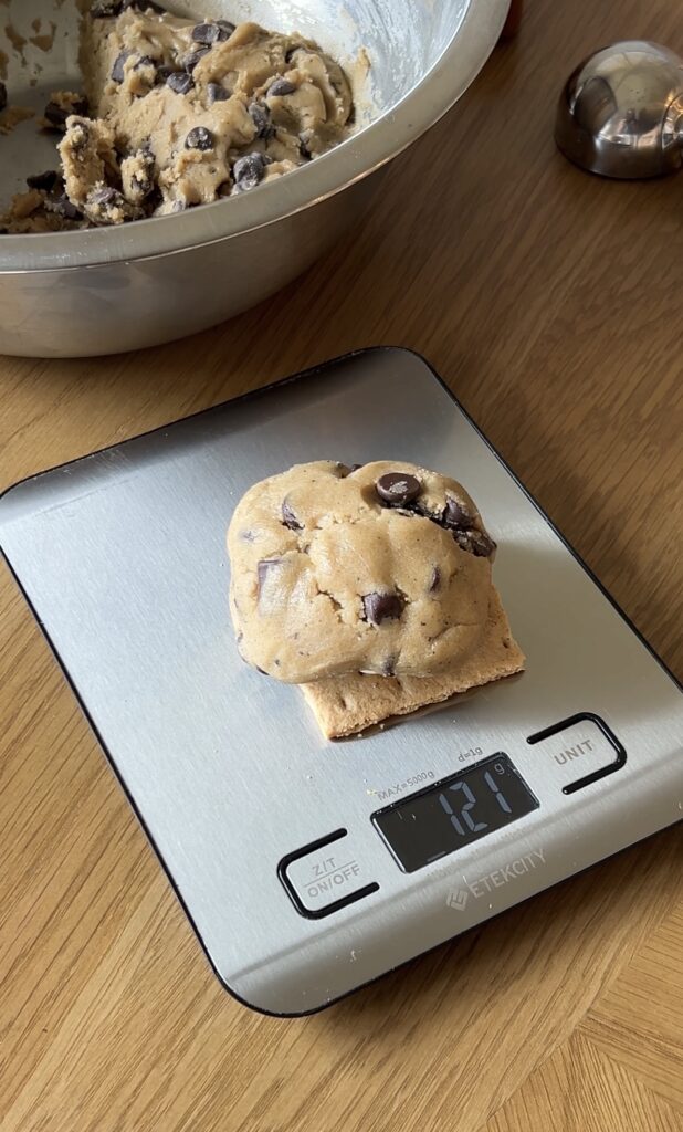 Stuffed s’mores cookie being weighed to approximately 120 grams before baking