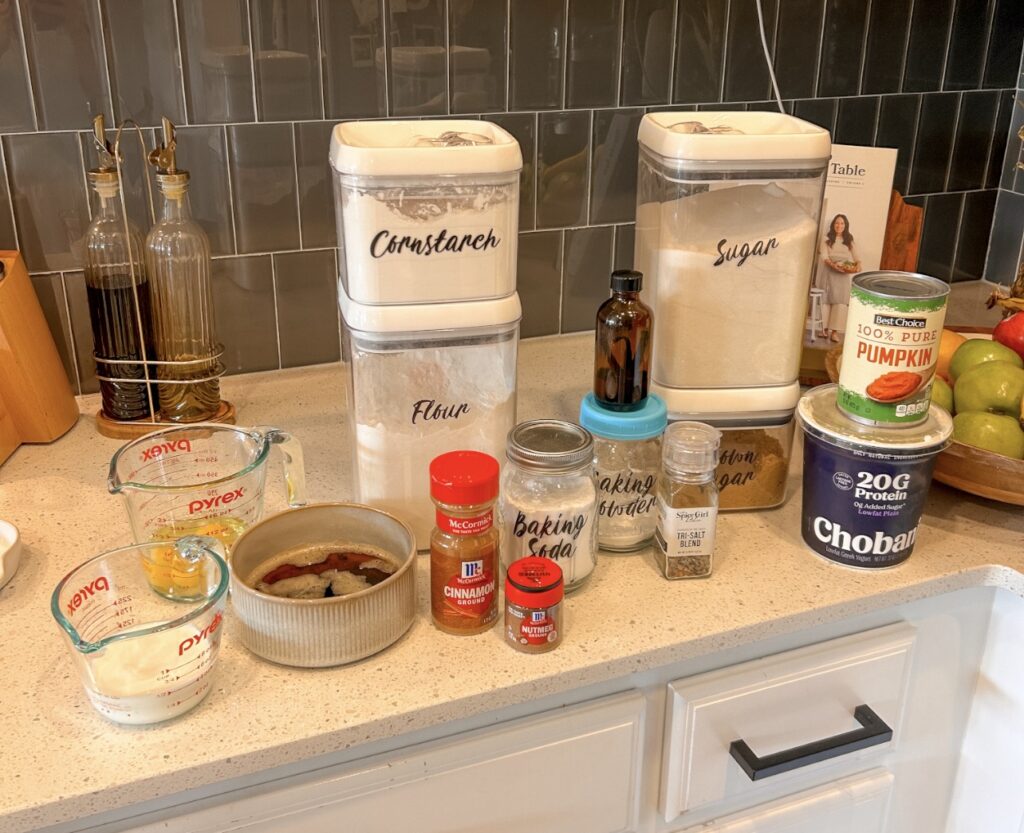 Ingredients for brown butter pumpkin bread including pumpkin puree, flour, eggs, butter, Greek yogurt, and spices.
