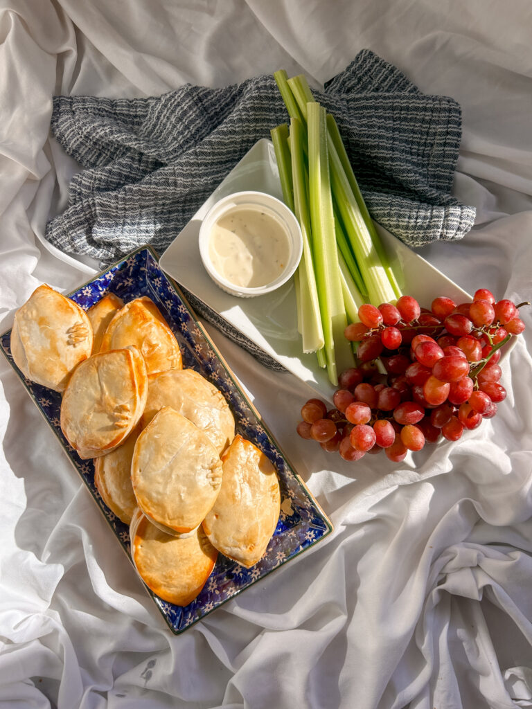 Football-shaped buffalo chicken hand pies with decorative pastry laces served with dipping sauce.