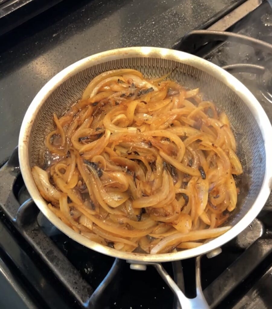 Sliced onions caramelizing in butter for cheeseburger bombs