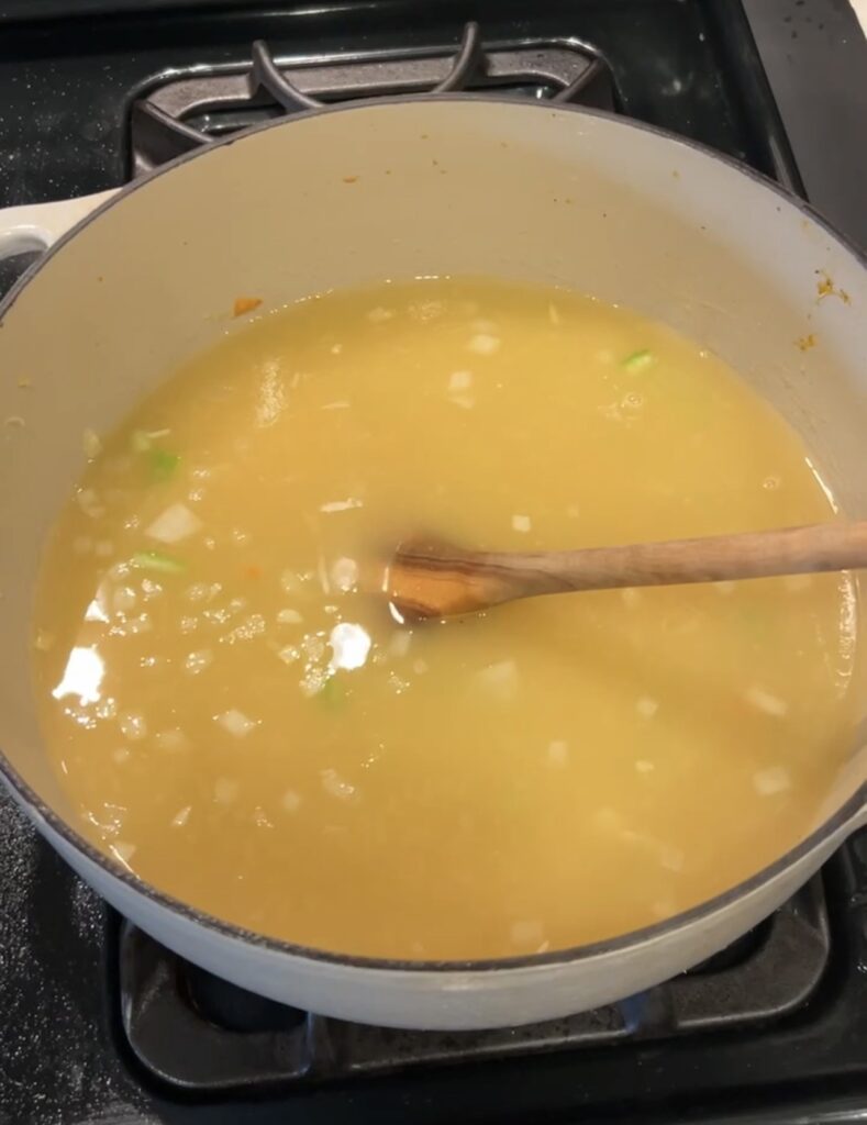 Chicken broth stirred into the flour and vegetables to build the soup base.