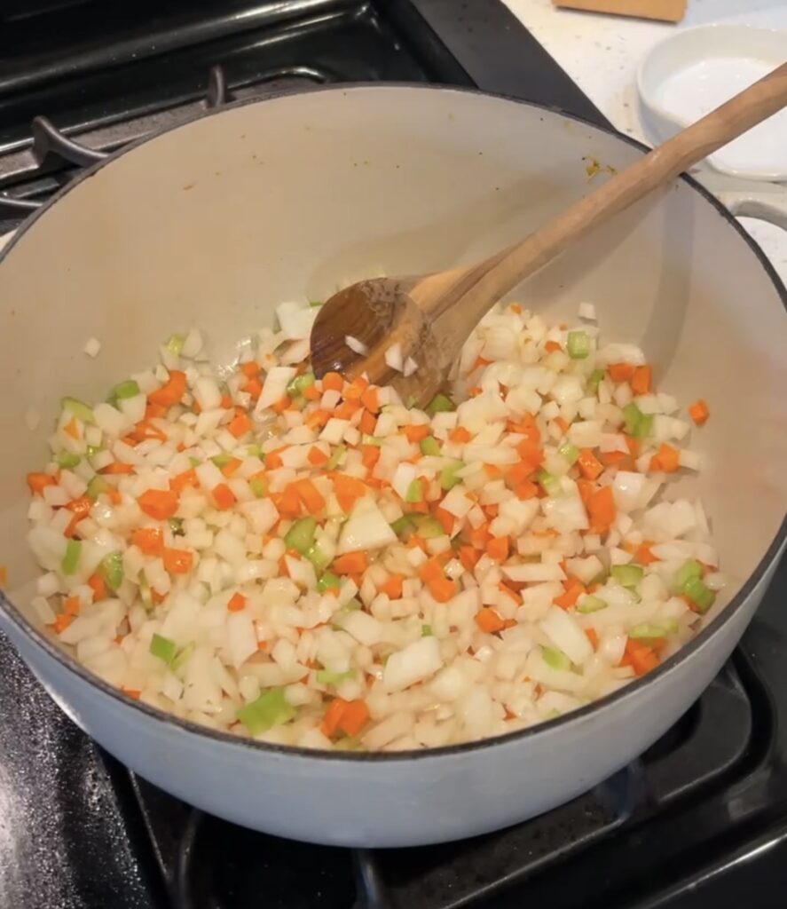 Diced onion, carrots, and celery cooking in butter and olive oil in a soup pot.