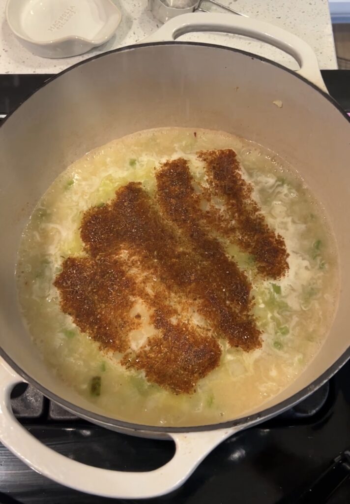 Flour, stock, and Cajun seasoning stirred into sautéed vegetables to build the corn and crab bisque base.