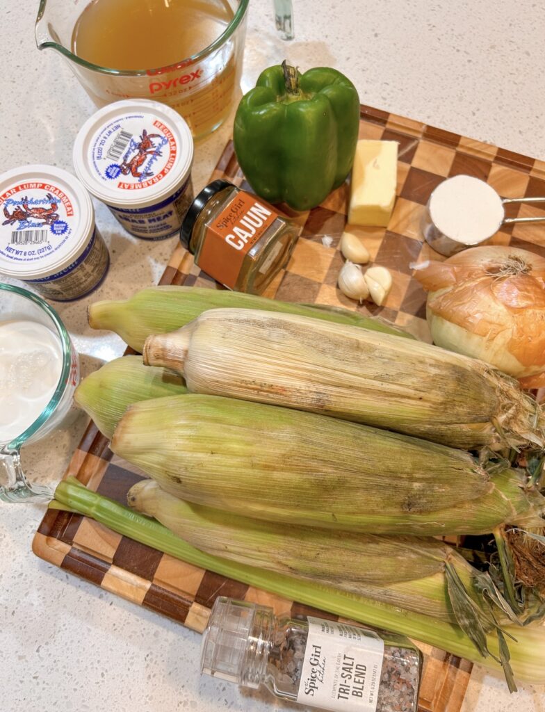 Ingredients for corn and crab bisque, including fresh corn, lump crab, vegetables, half-and-half, and Cajun seasoning.