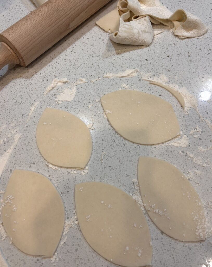 Refrigerated pie crust cut into football shapes for buffalo chicken hand pies.