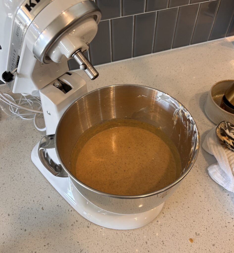 Pumpkin puree, eggs, sugar, Greek yogurt, milk, and browned butter mixed together in a bowl.